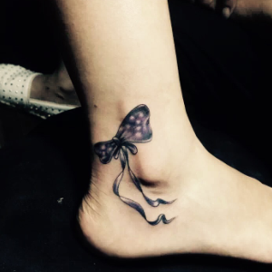 甜美的陆小姐脚踝处的可爱蝴蝶结纹身图案